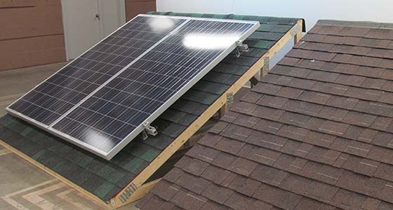 Solar Energy technicians looking at a laptop above installed panels.